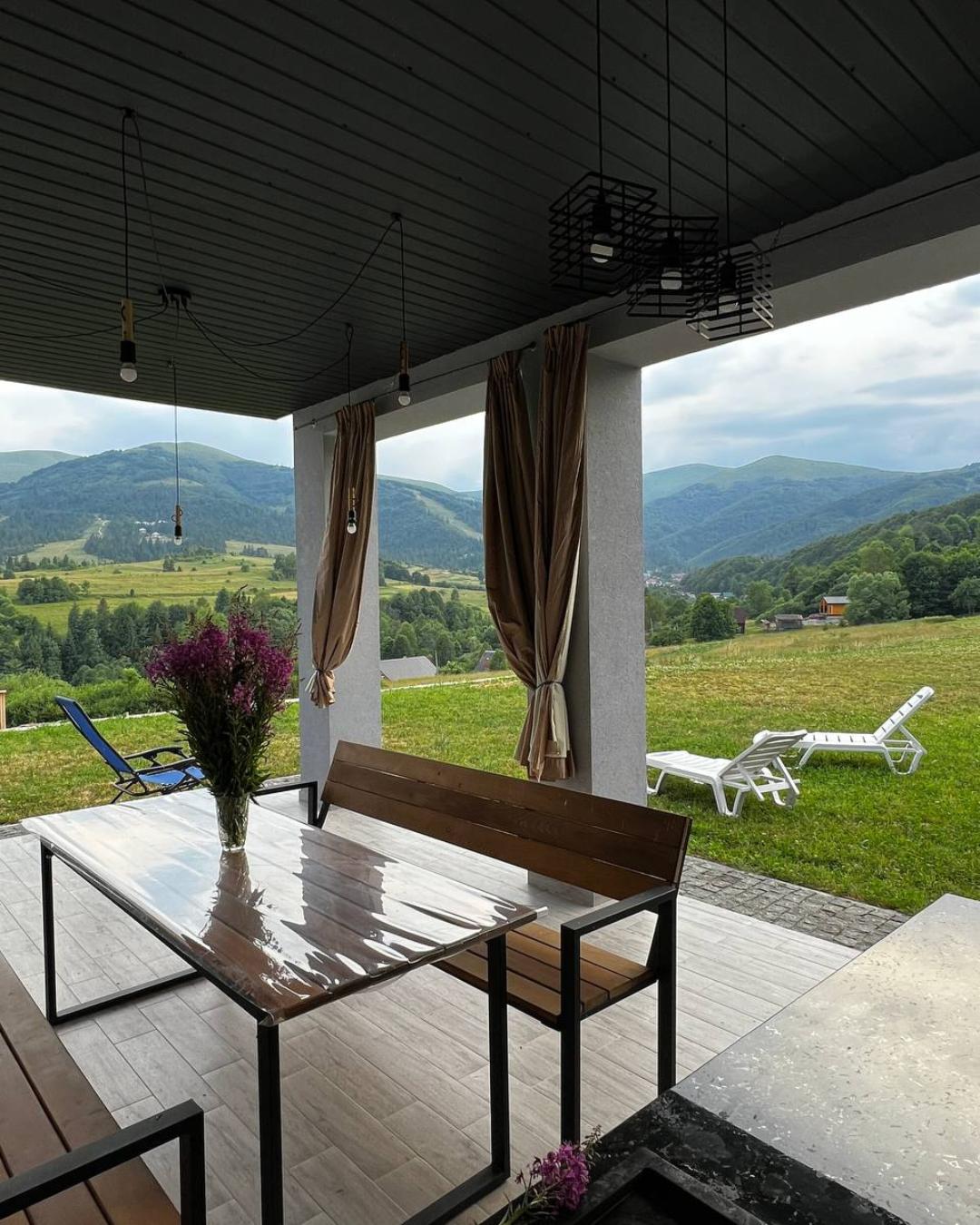 Літній вигляд котеджу Sota Ski Dream з терасою та зеленими горами на фоні.